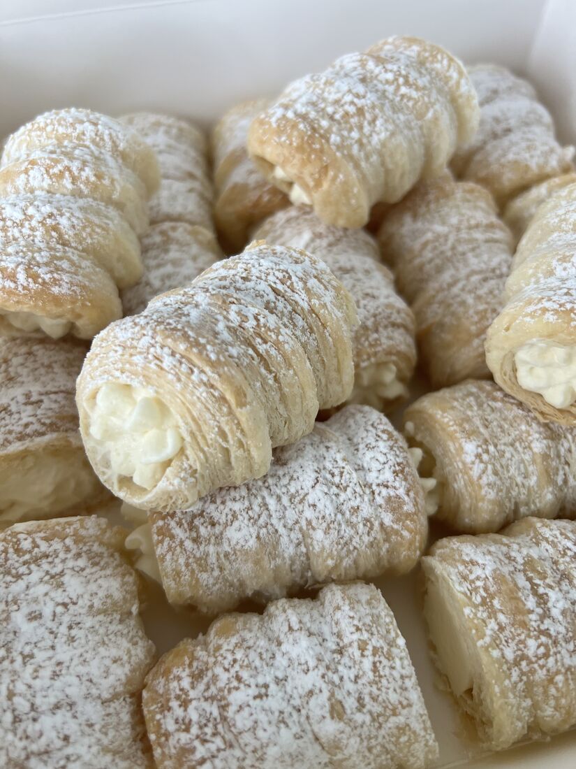 Full-size PastryVille cream rolls stacked and dusted with sugar