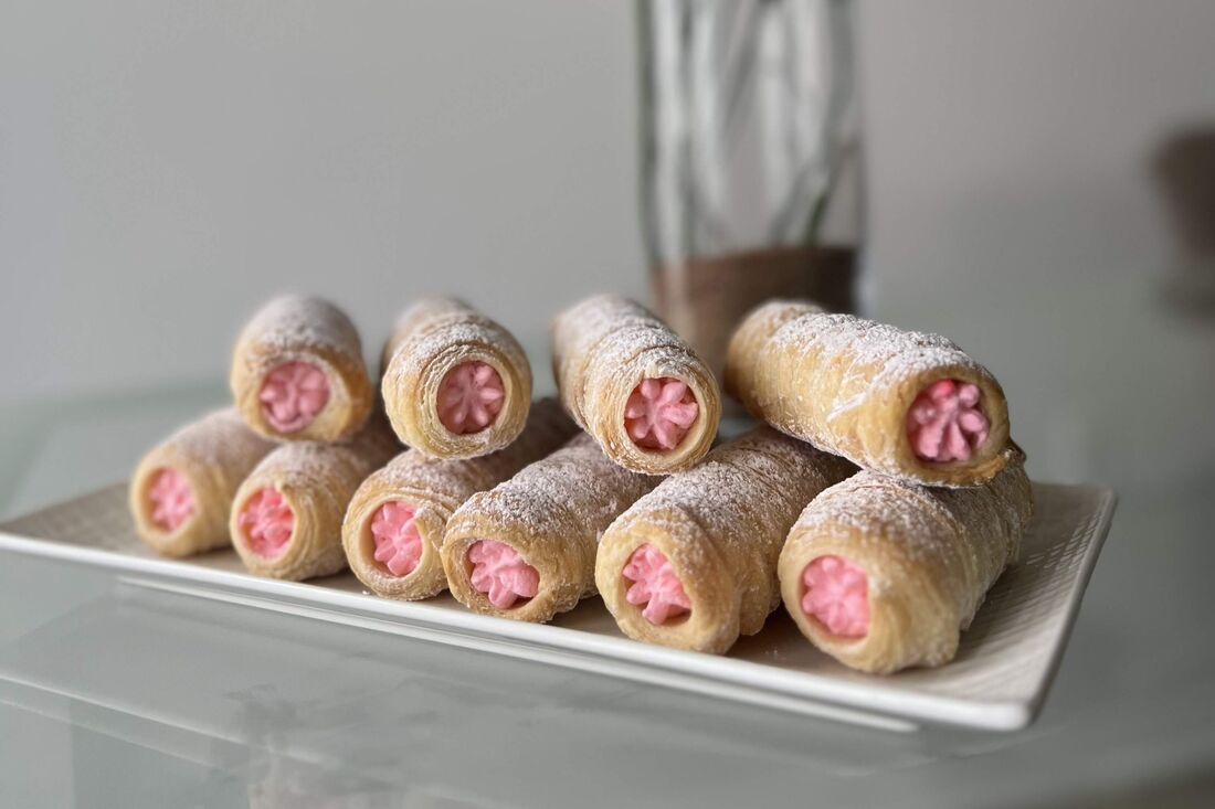 A tray of cream rolls with pink strawberry filling